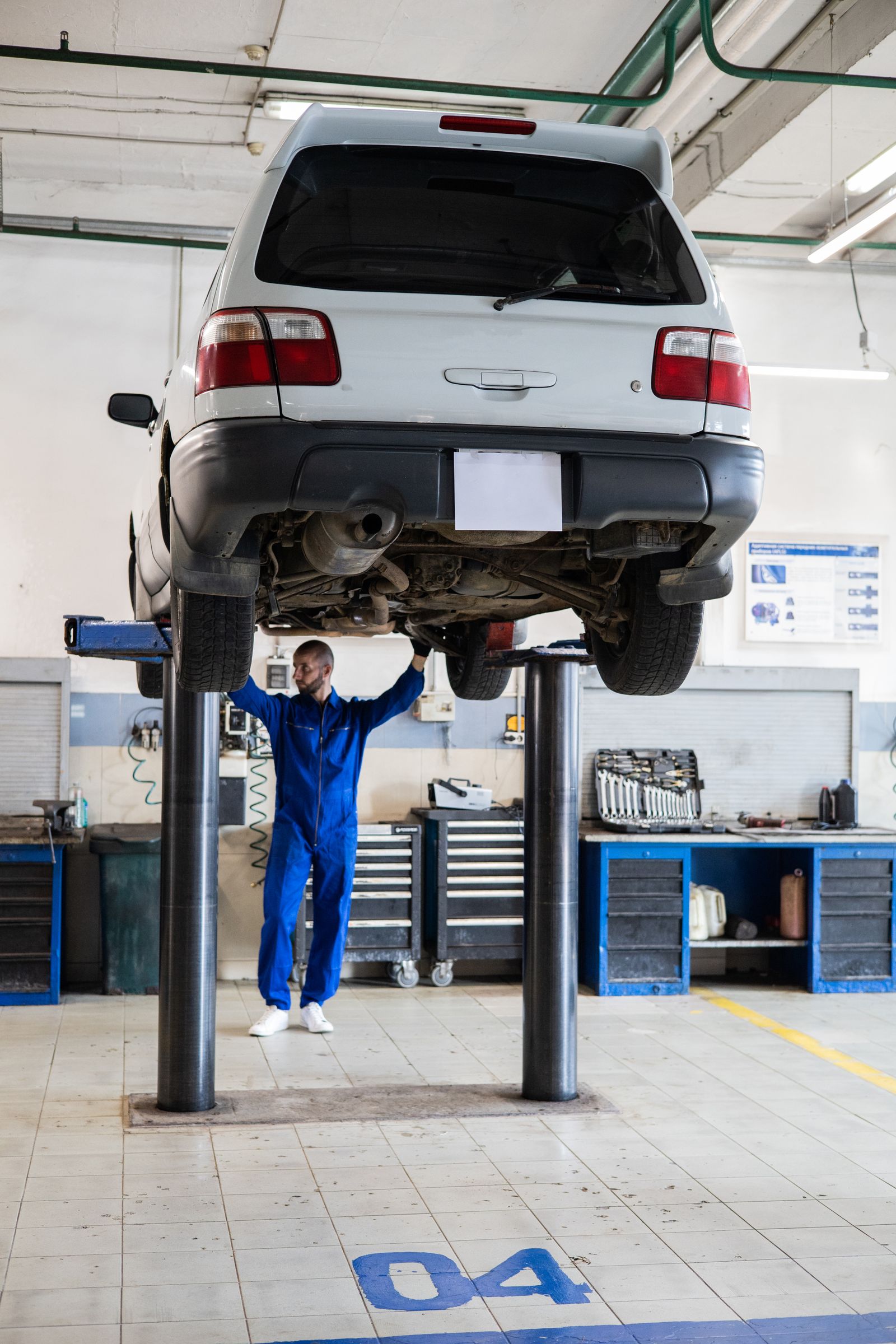 Mechanic working underneath a car raised on a workshop lift